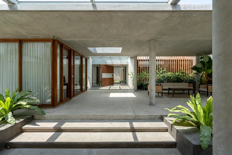 Interior courtyard with concrete steps, timber-framed glazing, and planted beds under skylights