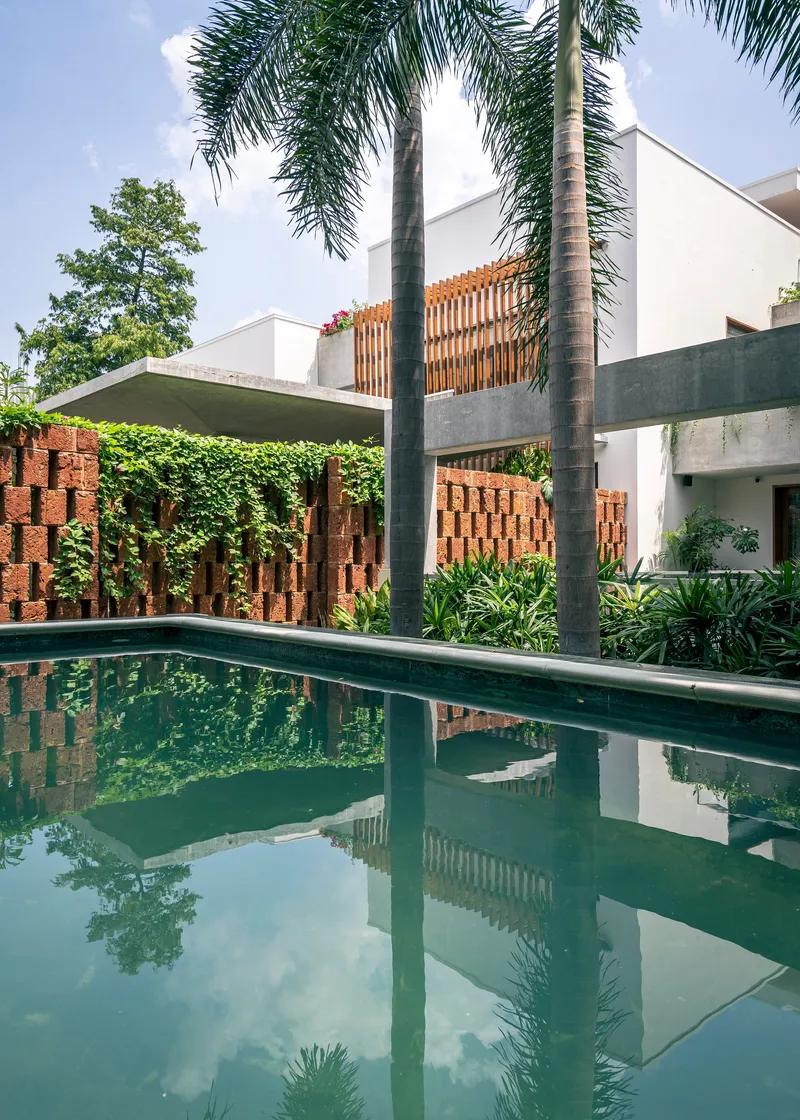 Pool courtyard with perforated brick privacy walls and palm trees reflected in still water