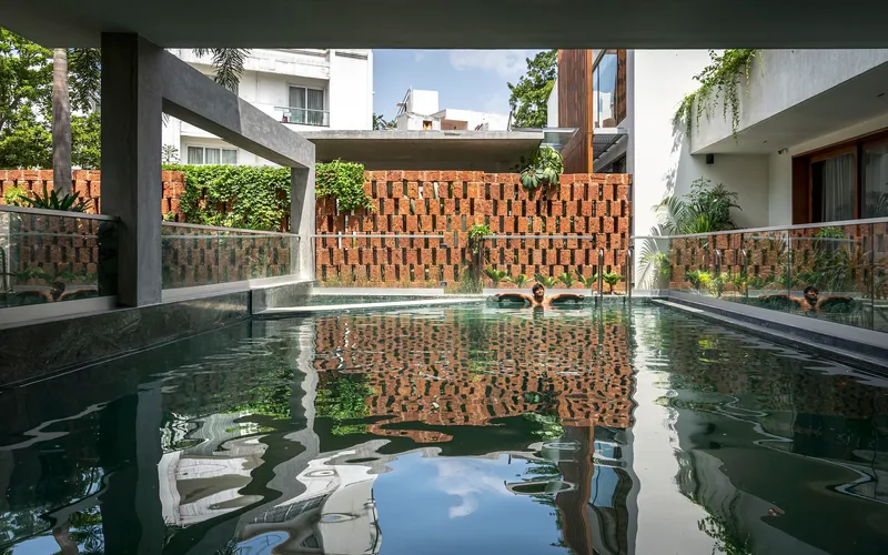 Reflecting pool bordered by brick screen walls and concrete beams framing interior rooms