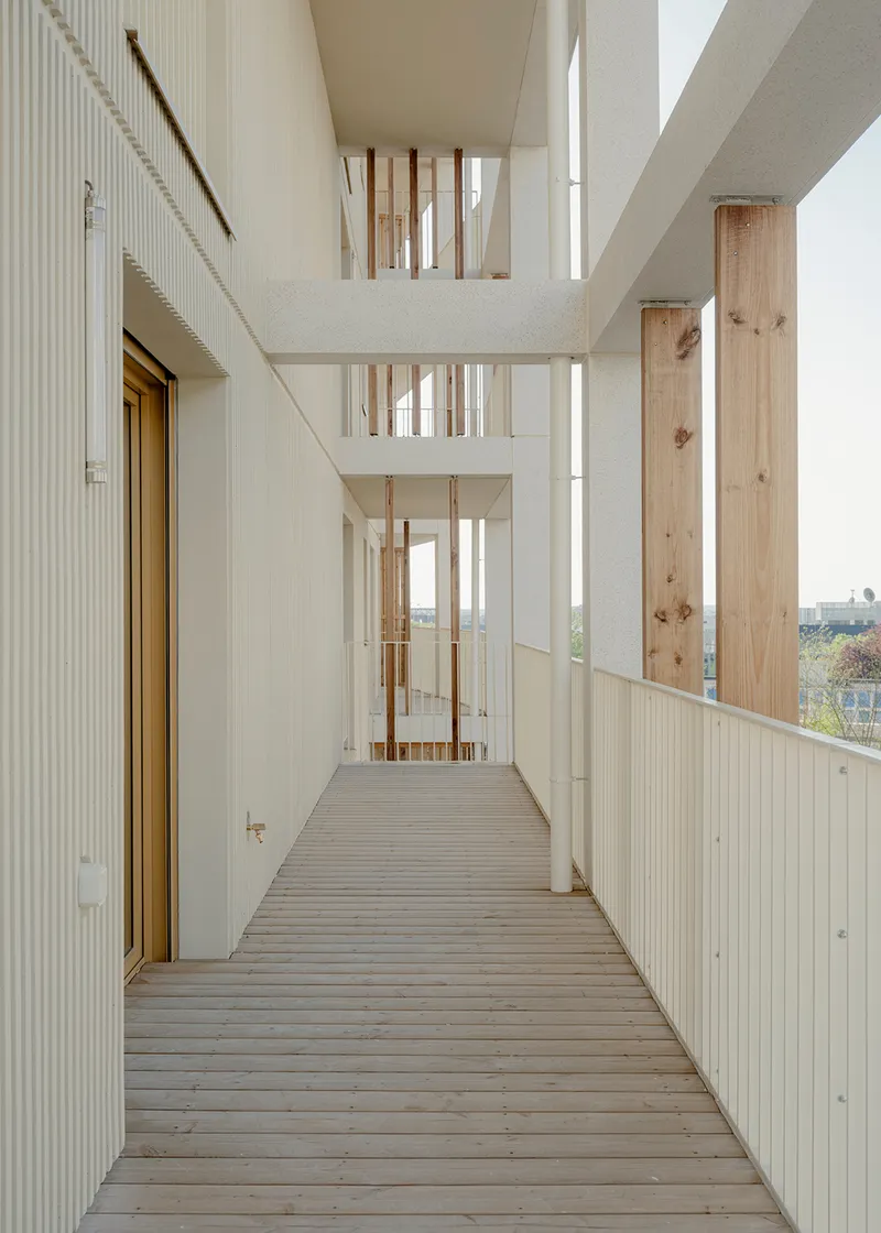 Timber-decked balcony with white corrugated panels and exposed timber columns framing vertical views