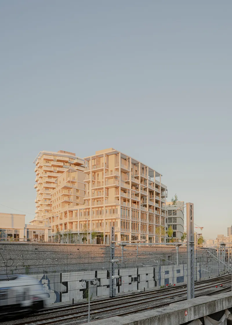 Timber residential block rising beside the railway tracks at dusk with a passing train