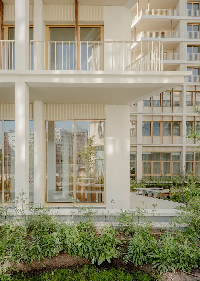 Ground floor unit with glazed doors opening to a planted garden bed in afternoon light