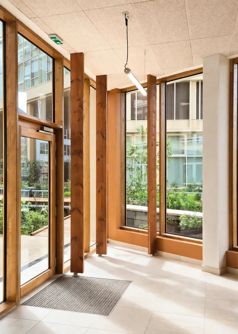 Entrance lobby with timber columns and floor-to-ceiling windows overlooking the planted courtyard