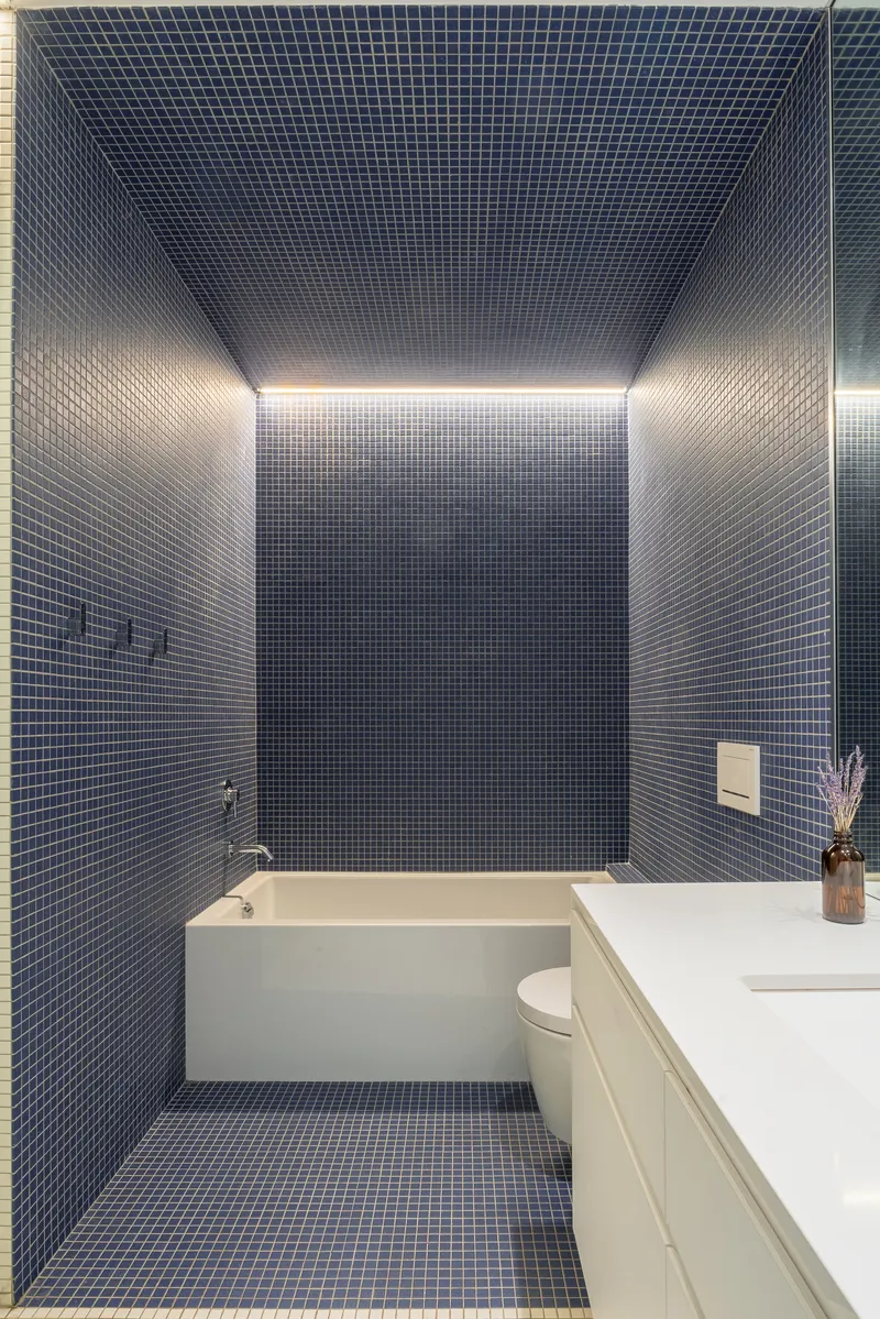 Bathroom with small blue mosaic tiles covering walls and ceiling, with concealed perimeter lighting