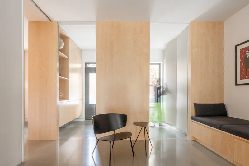 Hallway with pale wood partition panels, built-in bench seating, and polished concrete floor