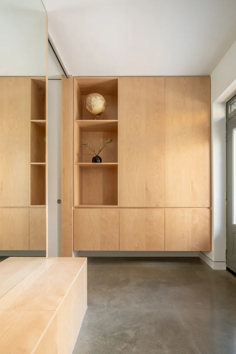 Light wood storage wall with open display niches holding a globe and small vase