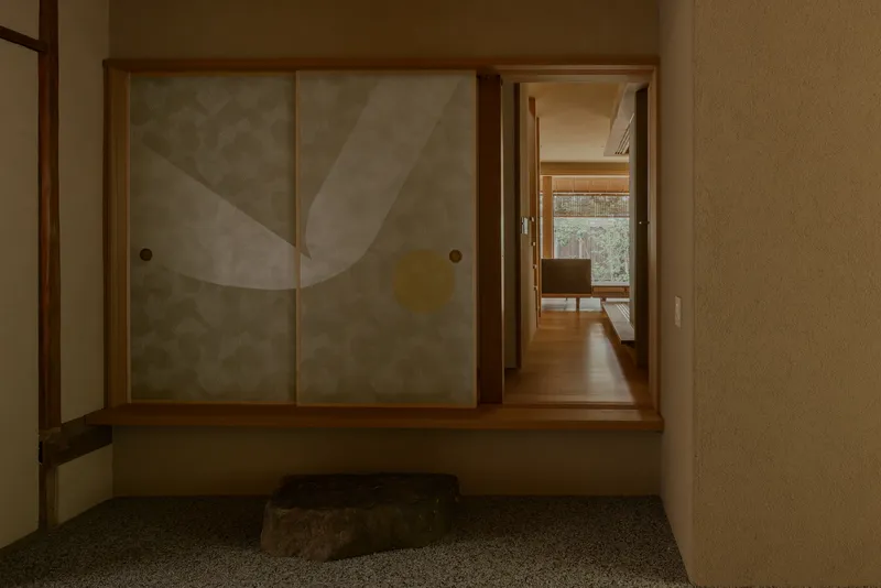 Entryway with translucent sliding doors, timber framing, and stone accent in terrazzo floor