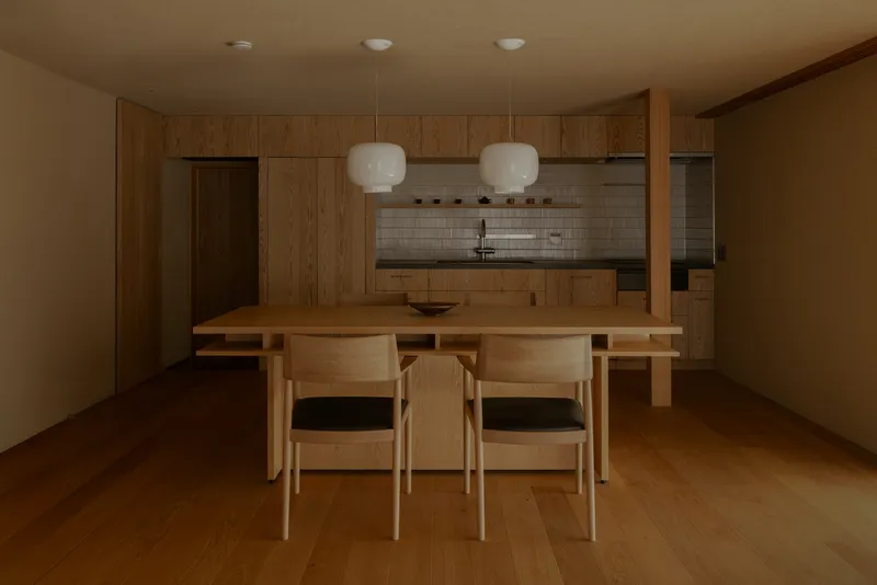 Dining area with timber table, chairs, and wood cabinetry beneath pendant lights