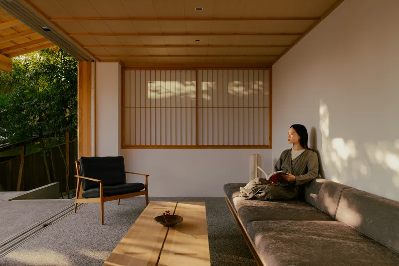 Covered terrace with person reading on curved bench beneath dappled afternoon light