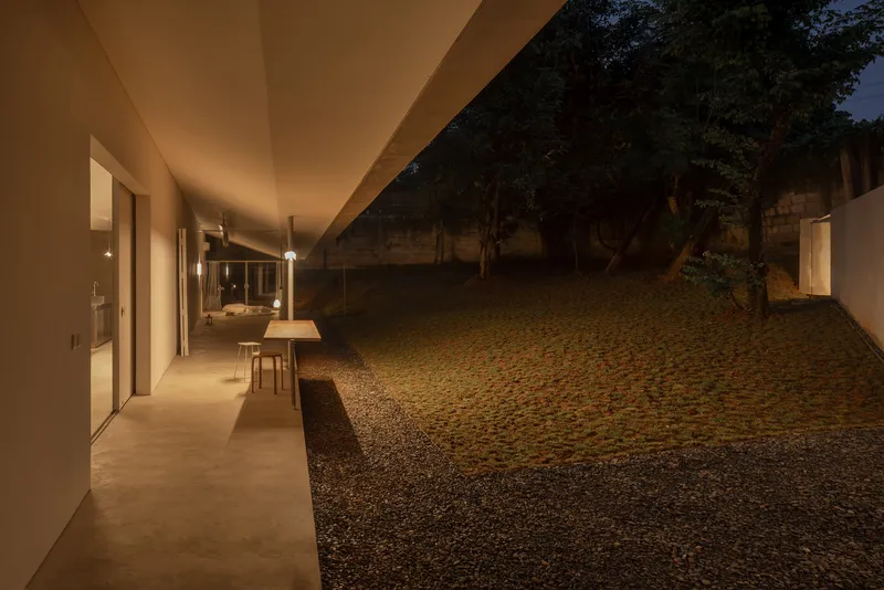 Covered walkway with polished concrete floor and gravel courtyard illuminated at night