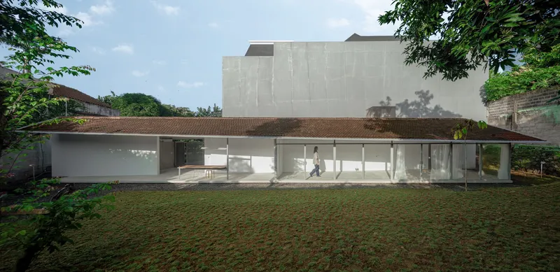 Garden view of the single-story pavilion with glass walls and tiled roof framed by mature trees