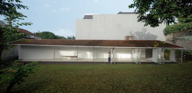Rear facade showing the glass-enclosed pavilion beneath the tiled roof with two figures visible inside
