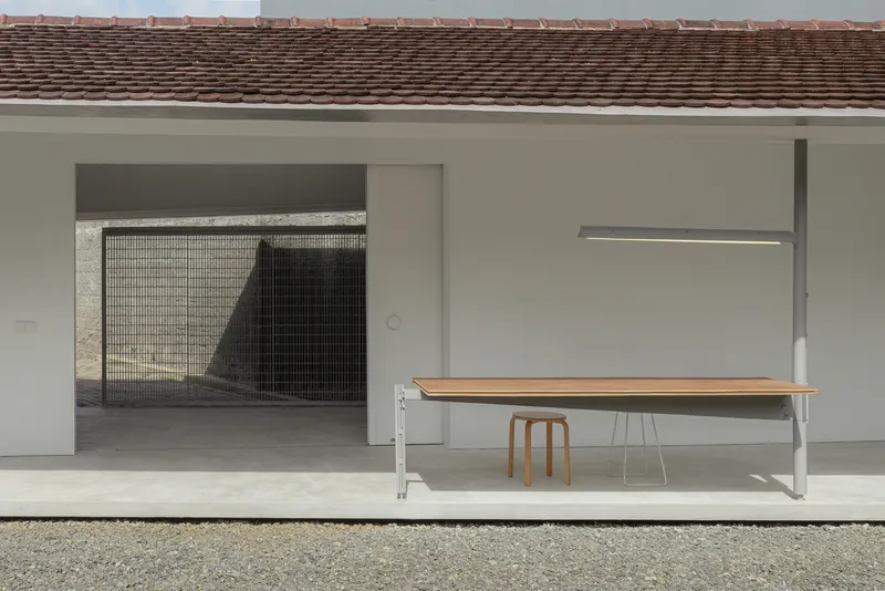 Covered terrace with a wooden bench and mesh screen opening beneath a tiled roof overhang