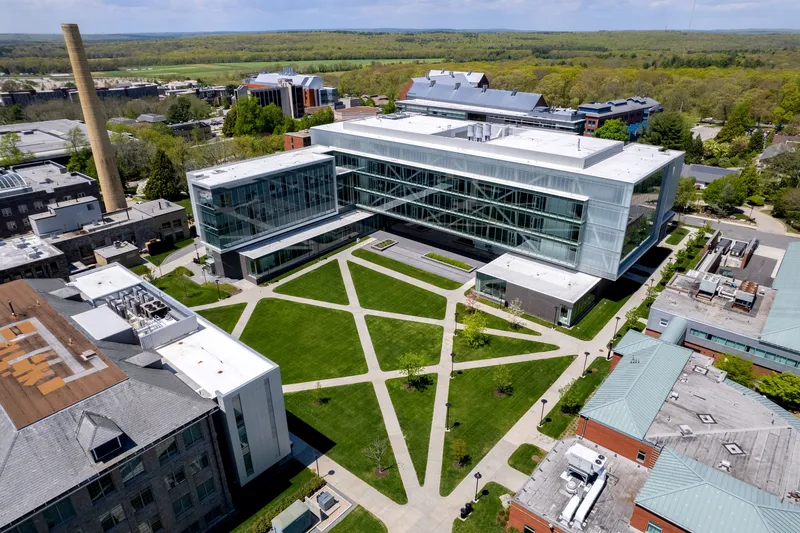 Aerial view of the glass and metal facade overlooking a geometric courtyard with diagonal lawn pathways