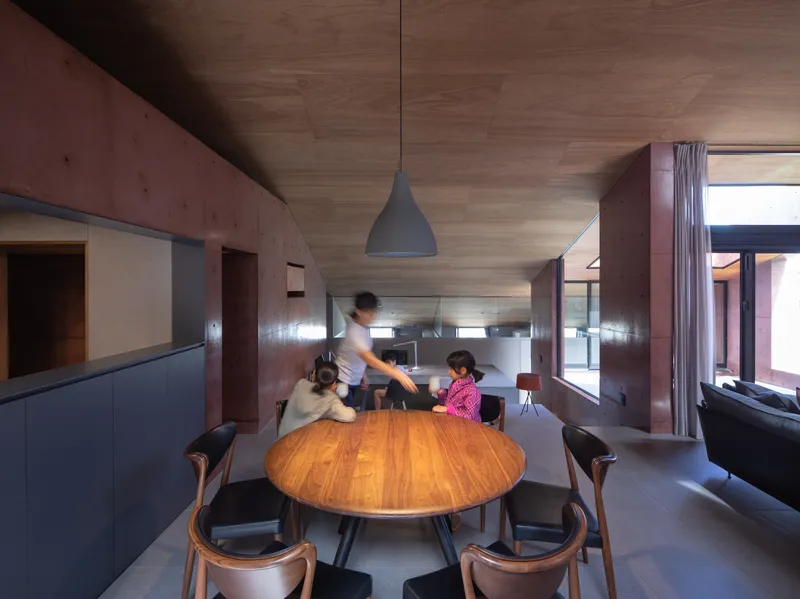 Dining area with round timber table where a family gathers beneath a pendant light