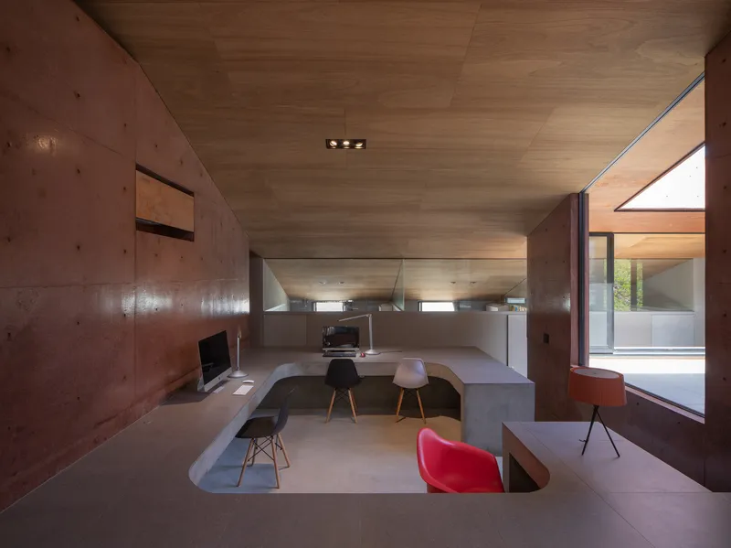 Sunken study area with built-in concrete desks and ribbon windows framing exterior views