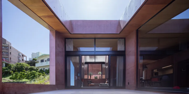 Covered terrace framing views through timber-clad volumes to a glazed courtyard beyond the neighborhood