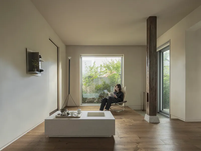 Interior room with picture window framing bamboo while a person reads in a chair