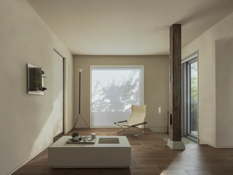 Living space with a low table, lounge chair, and translucent screen filtering tree shadows