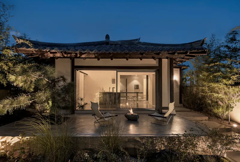 Curved tile roof with exposed rafters overlooking a terrace and garden at twilight