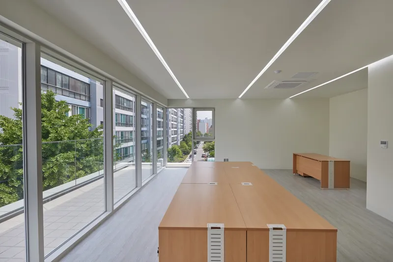 Office space with recessed linear ceiling lights and sliding glass doors overlooking green courtyard