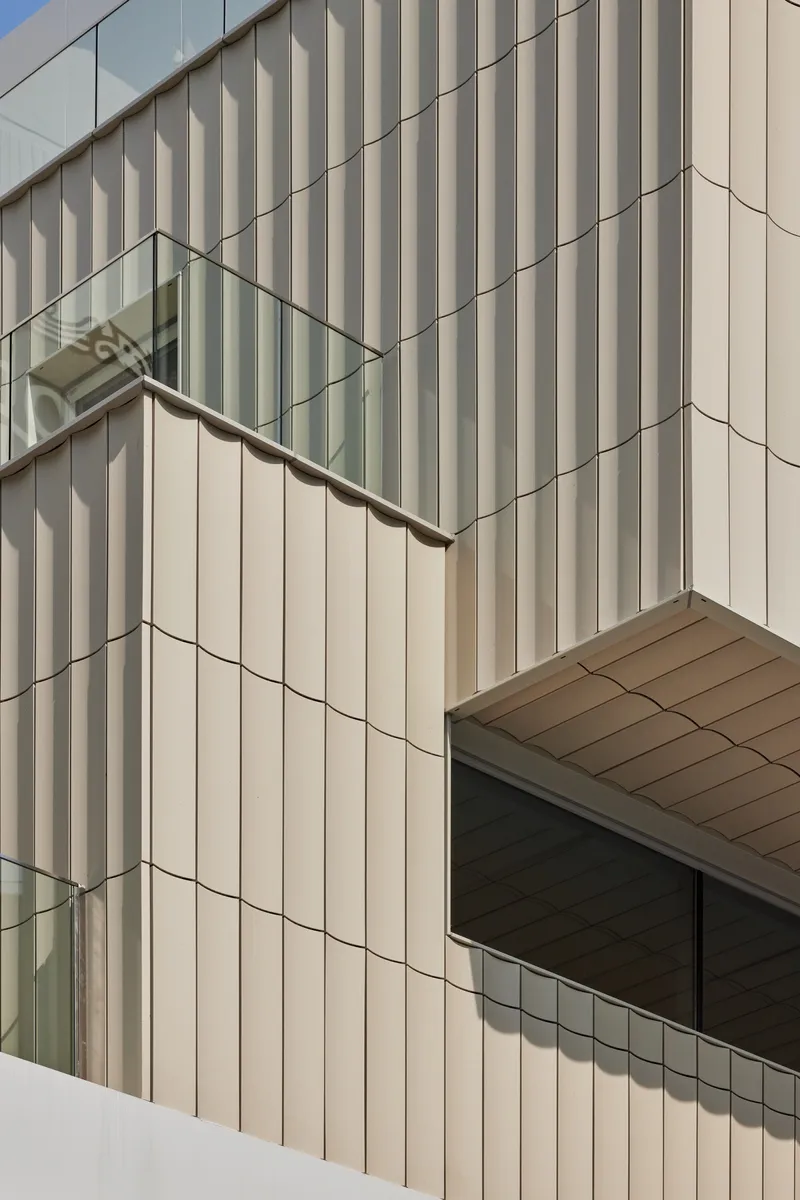 Corner detail of vertical corrugated metal cladding with horizontal window slot and soffit panels