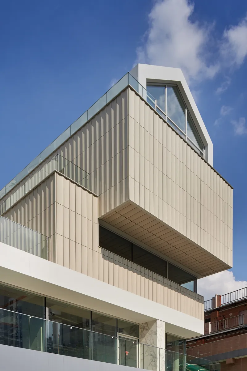 Oblique view of the vertical metal panel facade with cantilevered volume and recessed terrace