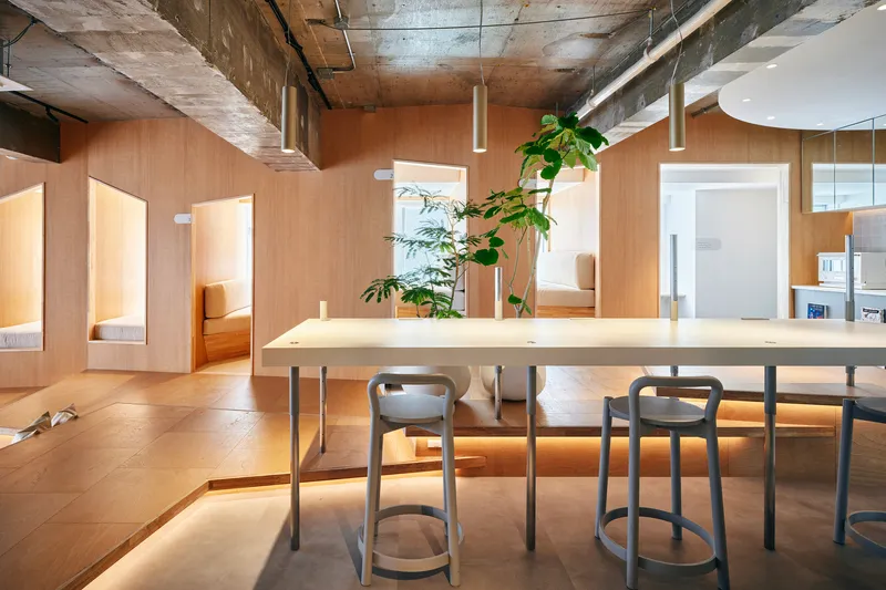 Plywood dining table with pendant lights and arched openings framing sleeping alcoves beyond