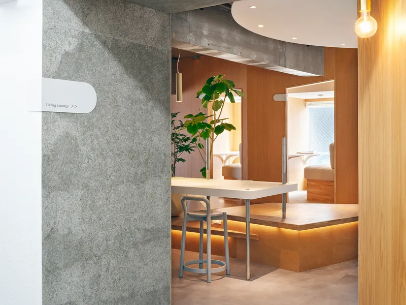 Concrete wall signage beside timber-framed alcove opening with bar-height table and stool