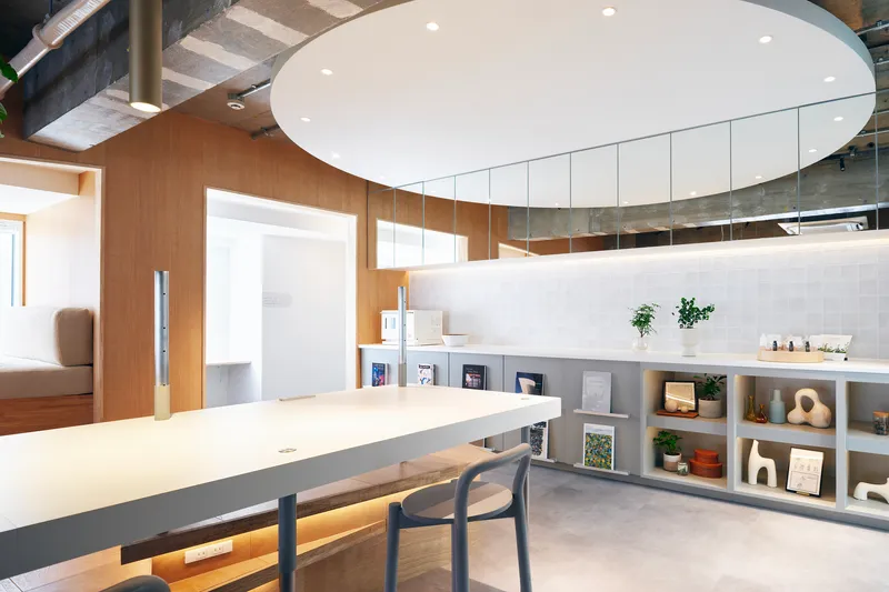 Kitchen counter with suspended white ceiling disc and open shelving below tiled backsplash