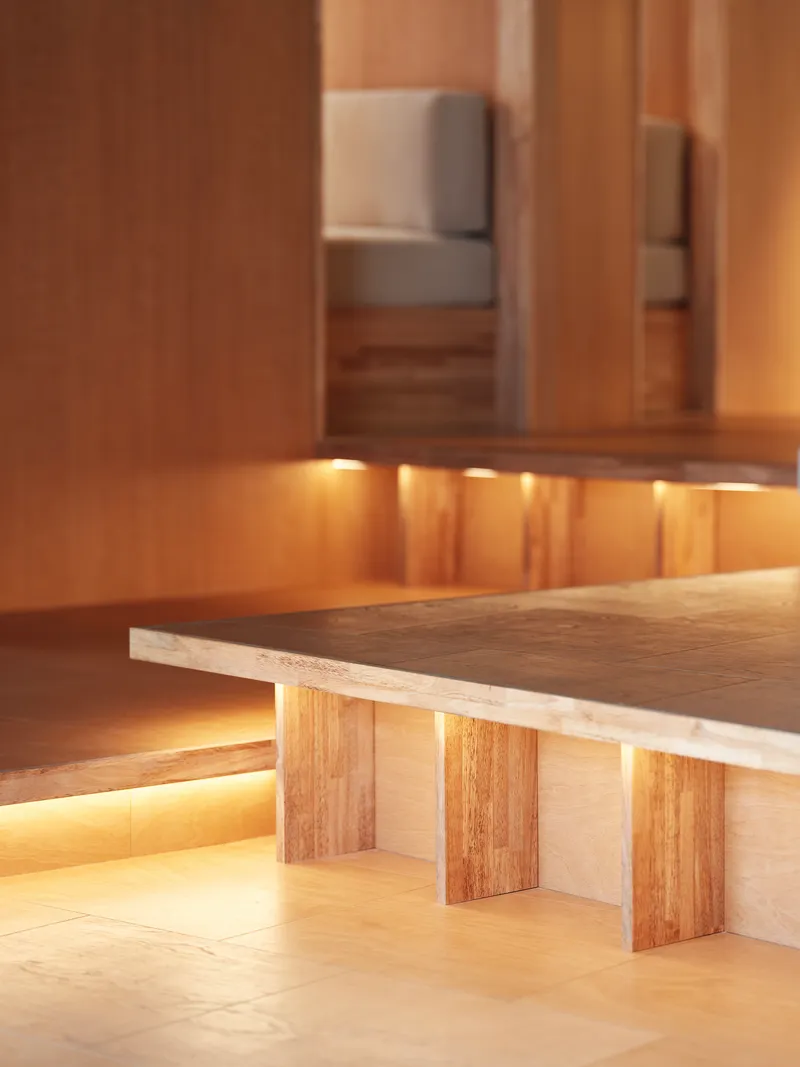 Low table with timber legs and integrated strip lighting beneath wood cabinetry with recessed cove illumination