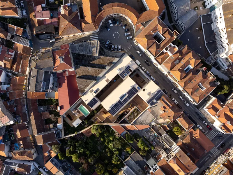 Aerial view of a rectangular courtyard with solar panels on the roof surrounded by terracotta tile roofs