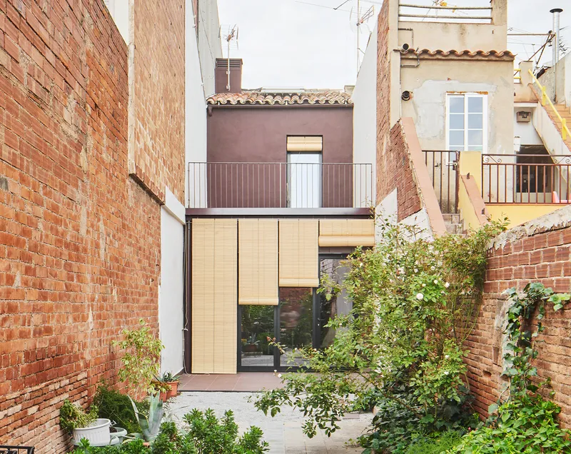 Rear courtyard view of the pale timber and glass facade framed by exposed brick party walls