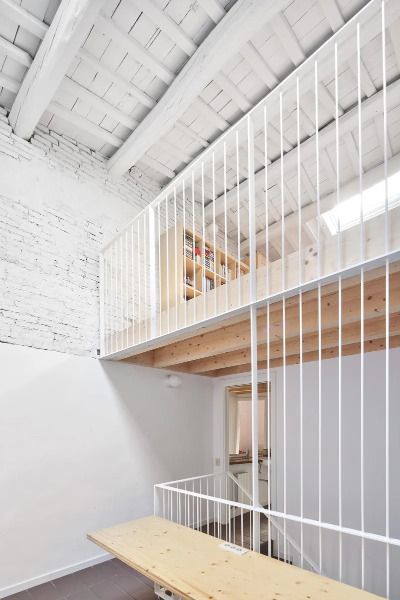 Interior view of white metal grid partitions enclosing mezzanine levels against exposed painted brick walls