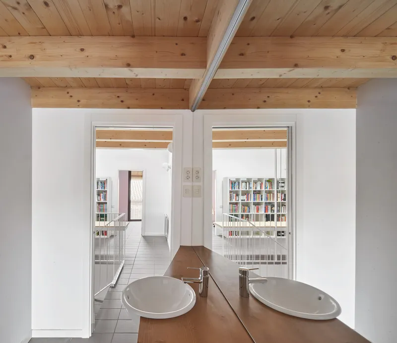 Bathroom vanity with timber countertop and twin sinks framed by doorways into circulation spaces beyond