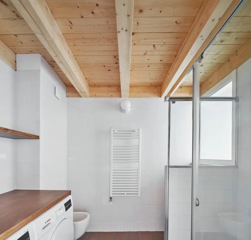 Bathroom with exposed timber beam ceiling, white tile walls, and a glass shower enclosure