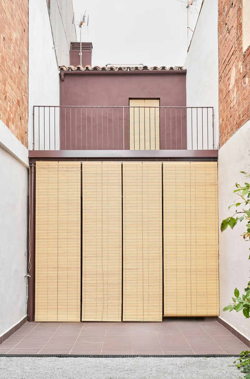 Rear facade with retractable timber slatted shutters fully closed over glazed openings between brick party walls