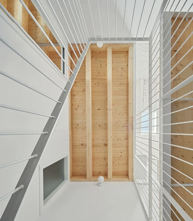 Three-story atrium with white metal railings and vertical timber-clad columns framing the central void