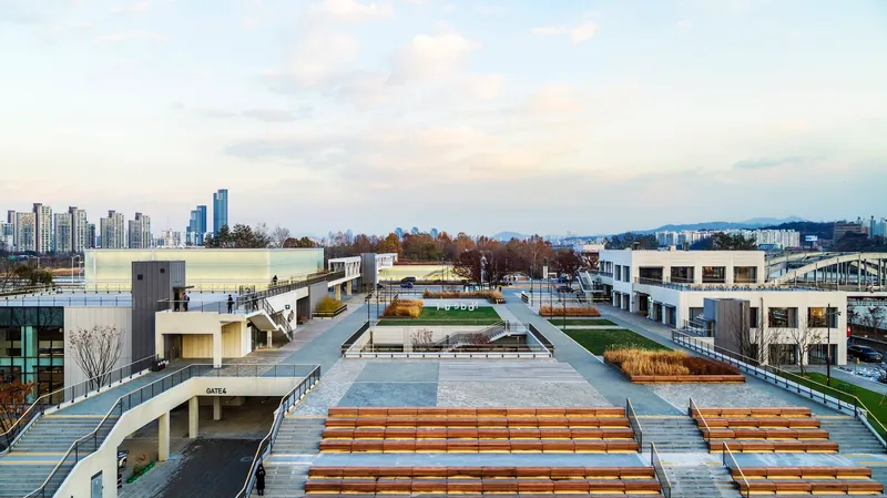 Rooftop plaza with stepped timber seating and planted beds overlooking the distant skyline at twilight