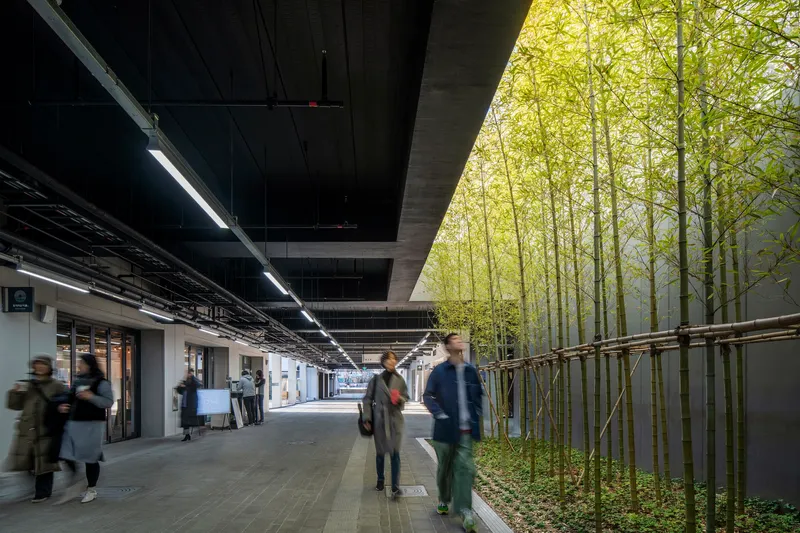 Covered platform corridor with bamboo planting along one edge under exposed concrete beams