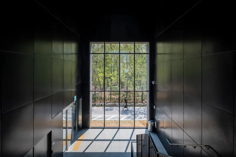 Double-height entrance lobby with gridded steel window framing a view of bare trees beyond