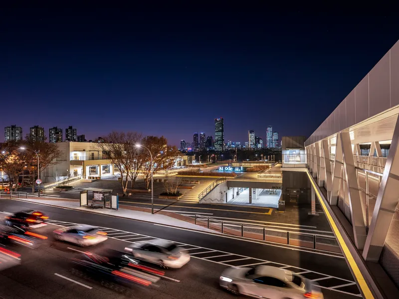 Aerial view of the pedestrian bridge and sunken plaza with city skyline at dusk