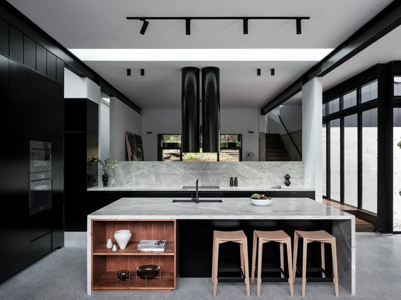 Kitchen island with marble waterfall edge and timber shelving nook beneath terrazzo flooring
