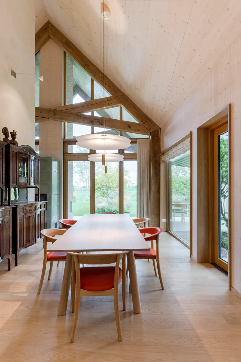 Dining room with exposed timber trusses and pendant light beneath a vaulted plywood ceiling