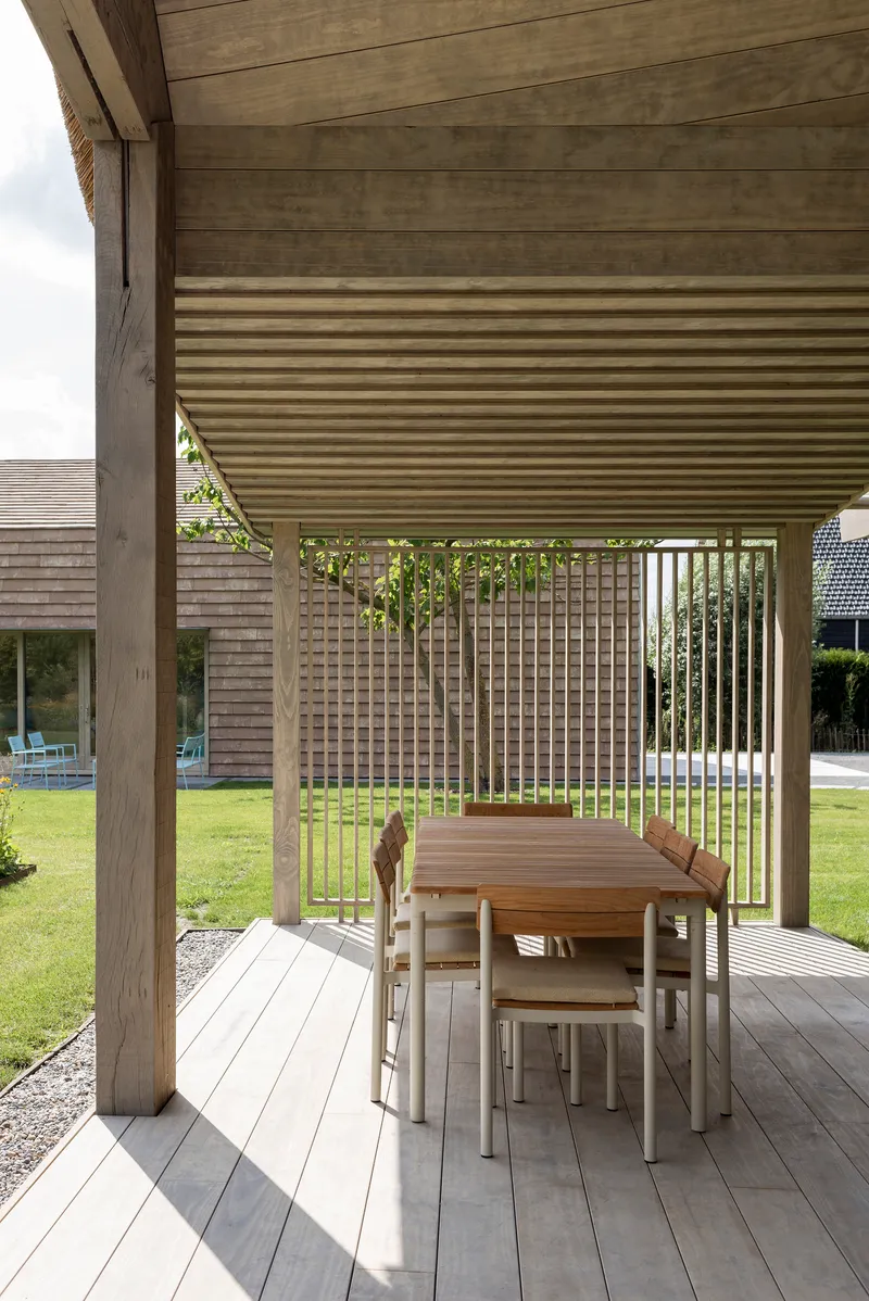 Covered terrace with timber decking and vertical slat railing overlooking a lawn