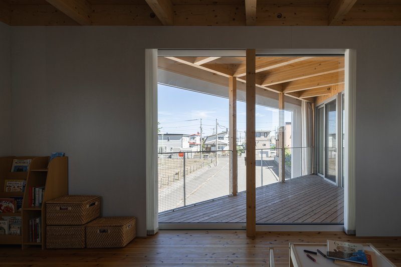 Interior view through sliding doors to the covered timber deck with exposed beam ceiling