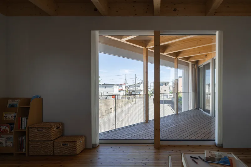 Interior view through sliding doors to the covered timber deck with exposed beam ceiling