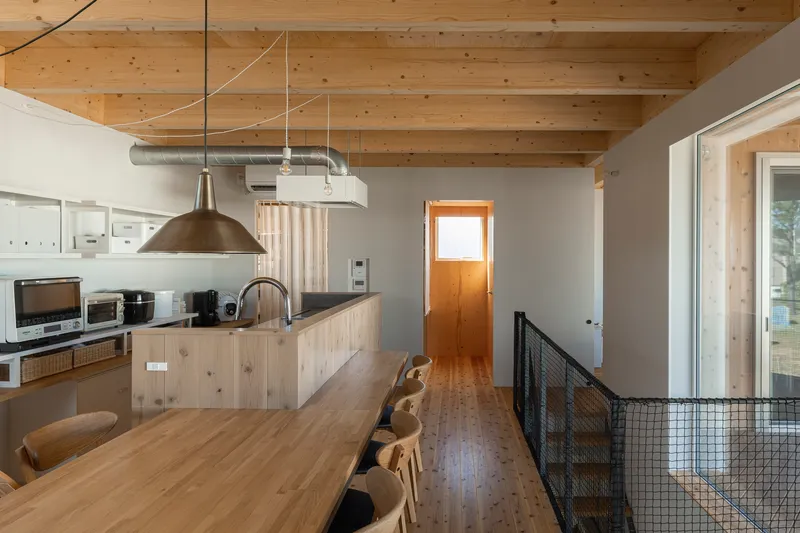 Open kitchen with timber island bench, exposed ductwork, and wire mesh guardrail at stair opening