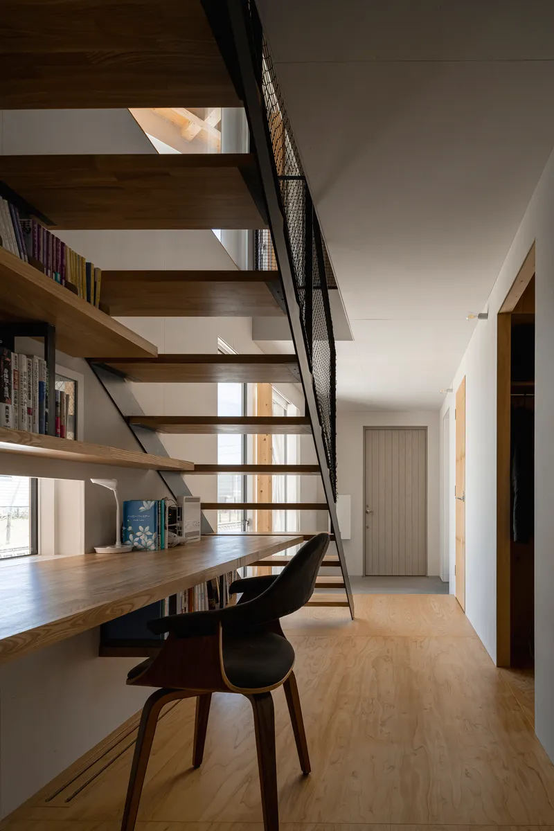 Open tread staircase with black steel frame and mesh rail alongside a built-in timber desk