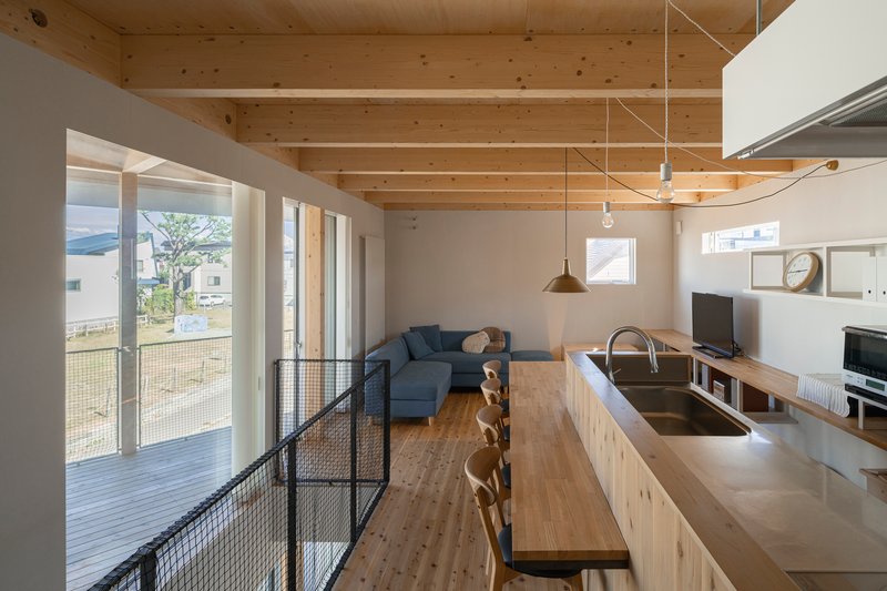 Kitchen island with stainless counter under exposed timber ceiling joists and pendant lights